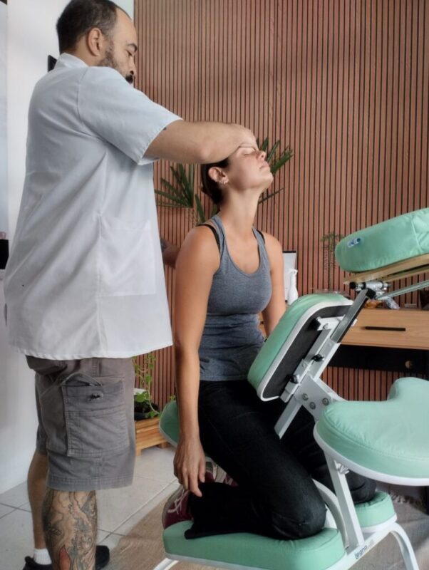 O que e quiropraxia — sem complicar terapeuta realizando mobilizacao cervical em paciente sentada na cadeira verde espaco TAO Curitiba