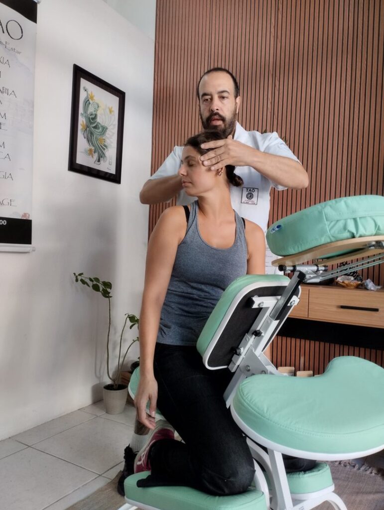 Tecnica Craniana Cabeca Paciente Espaco TAO Curitiba terapeuta aplicando tecnica manual na cabeca de paciente sentada cadeira verde Espaco TAO Curitiba