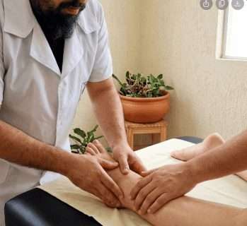 7 Sinais de Má Circulação nas Pernas (E Quando Parar de Ignorar) Má Circulação nas pernas? técnicas suaves de massagem de drenagem linfática manual no tornozelo e na parte inferior da perna de uma pessoa deitada em uma maca, com o objetivo de aliviar sintomas de má circulação.