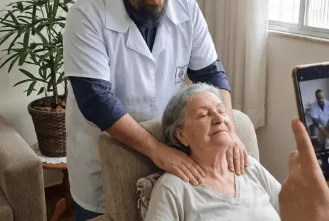 Massagem para Idosos: O Que Muda e Por Que Importa Massoterapeuta do Espaço TAO realizando massagem para idosos nos ombros e pescoço de uma mulher idosa em ambiente aconchegante.